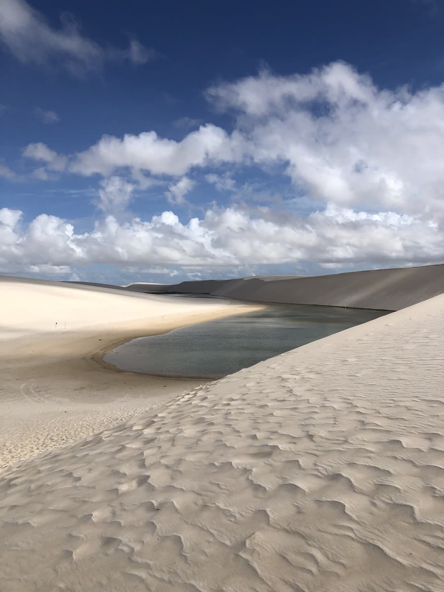 Duna branca e lagoa sob céu azul com nuvens